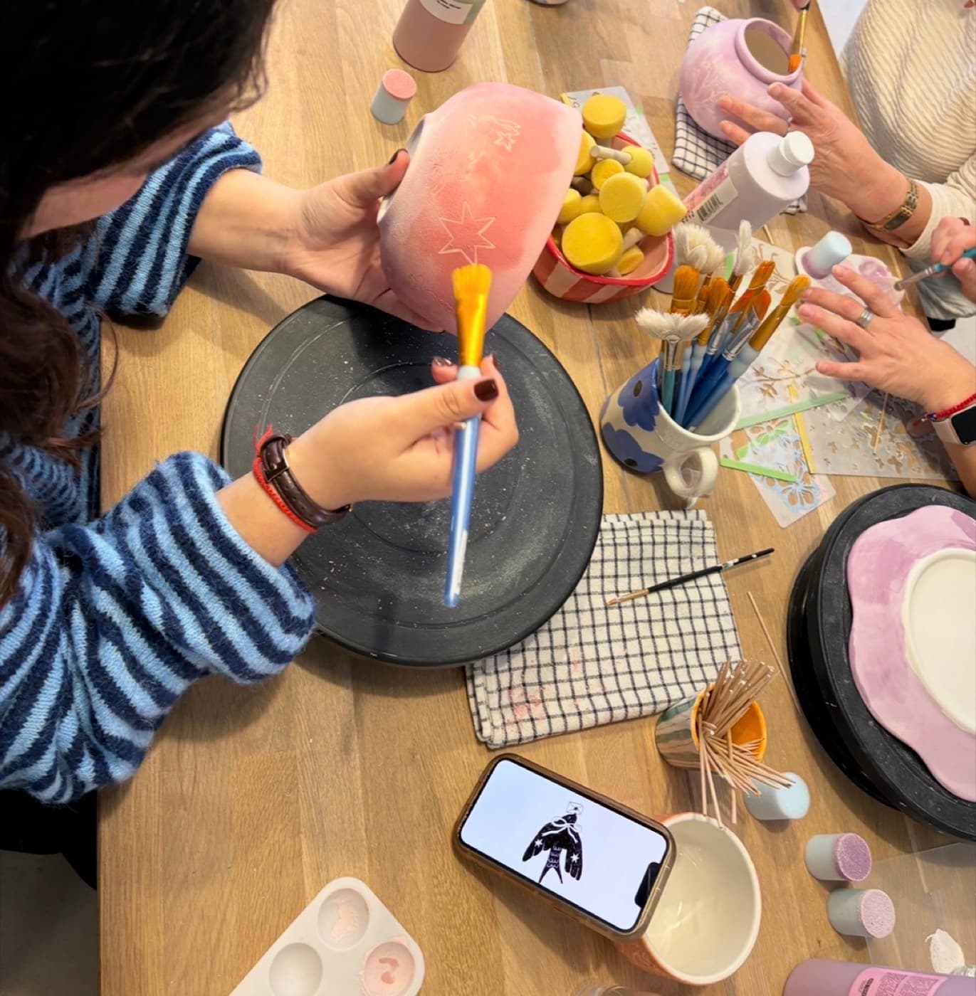 Grupo de amigas pintando cerámica alrededor de una mesa
